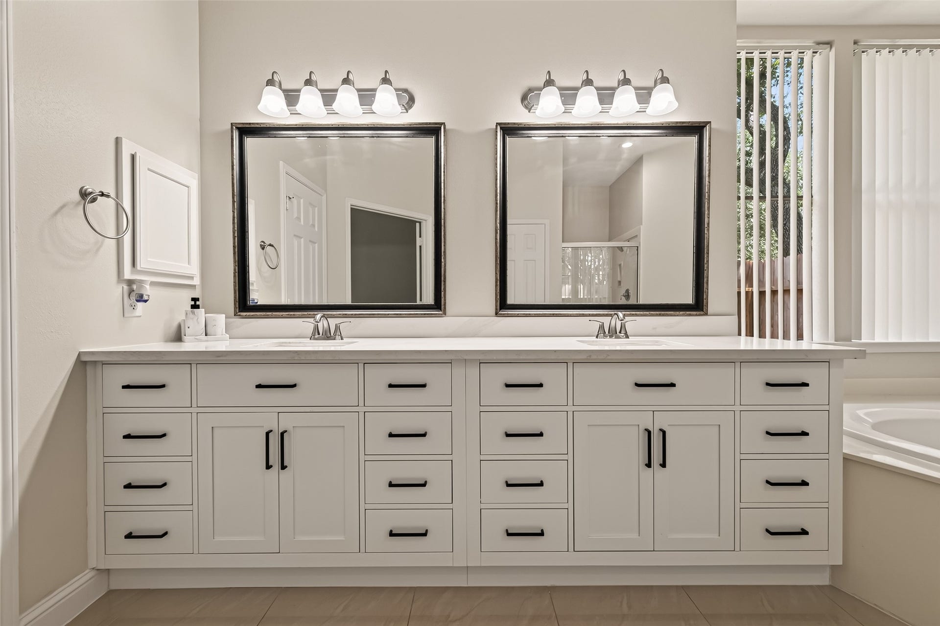 2002 Thorncrest Court, Sugar Land, TX 77479 Elegant double vanity bathroom with sleek white cabinetry, modern fixtures, and large mirrors, offering ample storage and style.