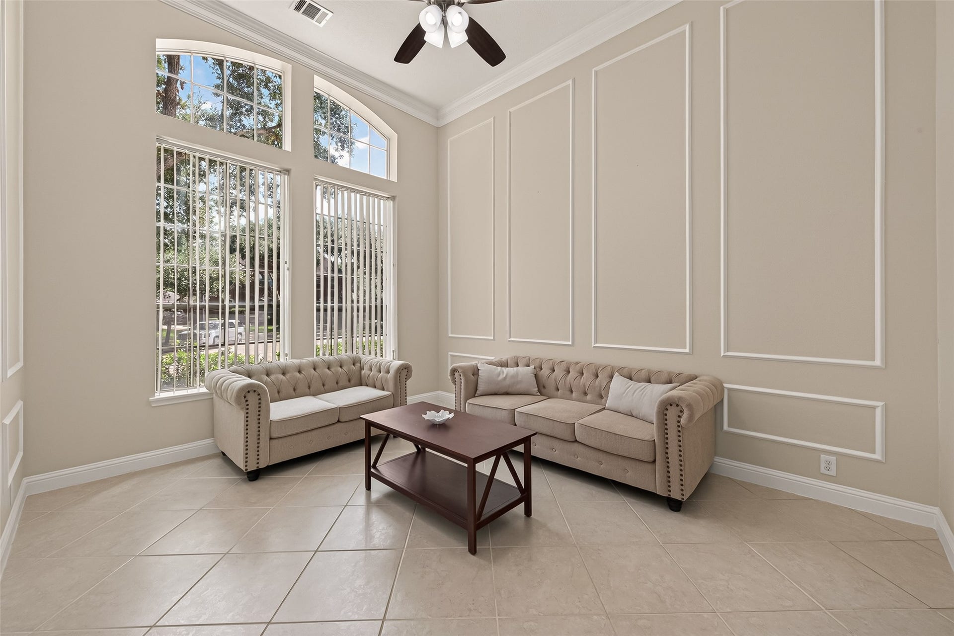 2002 Thorncrest Court, Sugar Land, TX 77479 Bright and inviting living space with elegant tan walls and large windows, featuring stylish tufted sofas and a sleek coffee table.