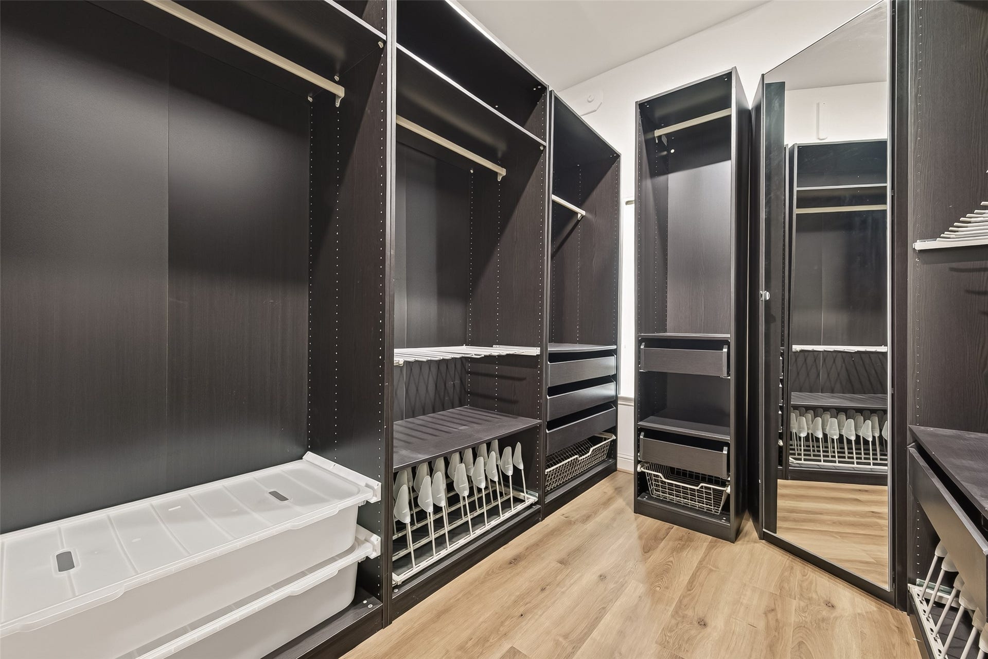 2002 Thorncrest Court, Sugar Land, TX 77479 Spacious walk-in closet featuring sleek dark wood shelving, ample storage options, and a full-length mirror, all set on elegant hardwood flooring.