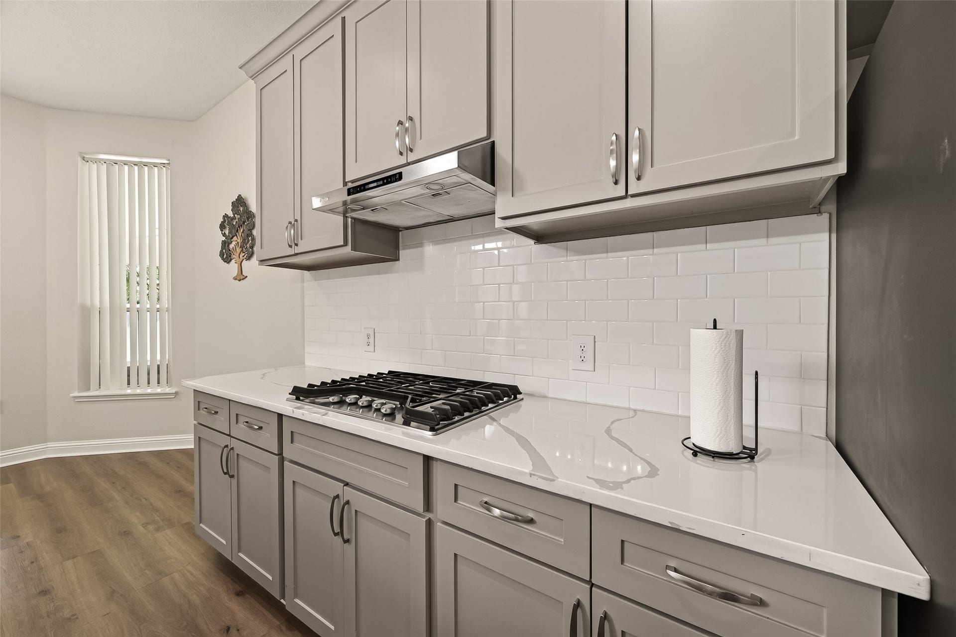 2002 Thorncrest Court, Sugar Land, TX 77479 Stylish kitchen with sleek gray cabinets, a modern gas cooktop, and a pristine white subway tile backsplash, all complemented by elegant wood flooring.