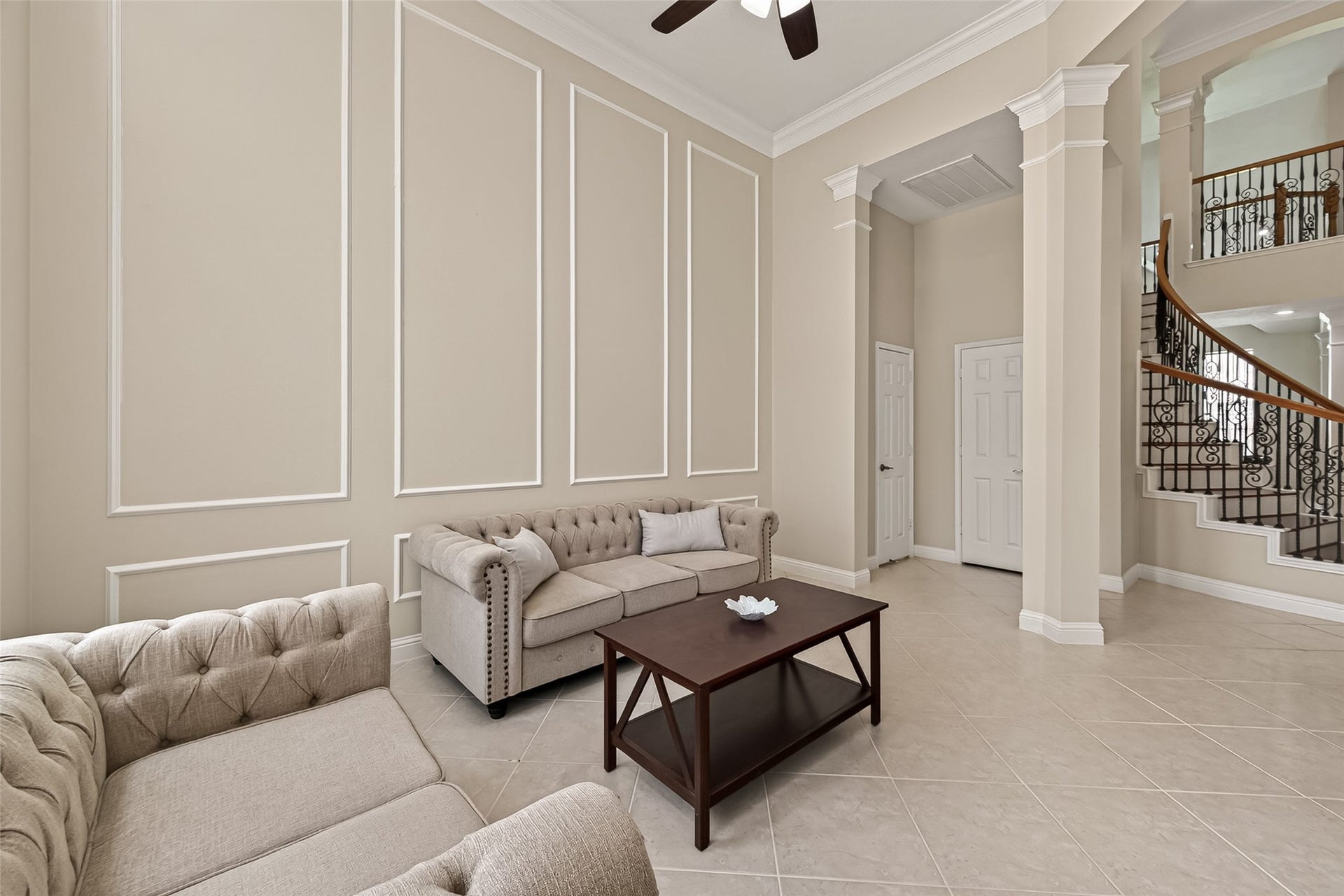 2002 Thorncrest Court, Sugar Land, TX 77479 Elegant living area with high ceilings, sophisticated wall paneling, and a graceful staircase.