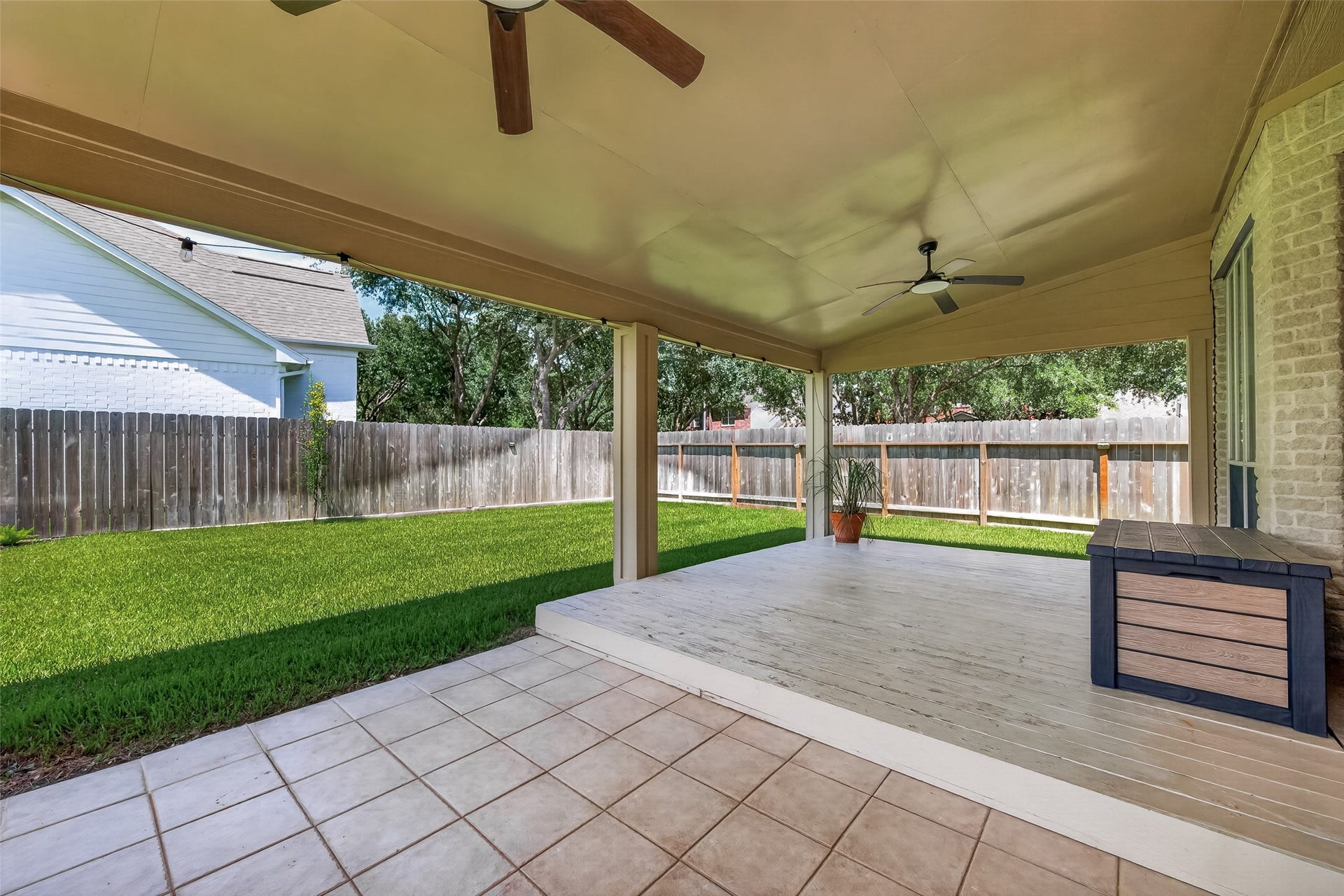 2002 Thorncrest Court, Sugar Land, TX 77479 Expansive covered patio with ceiling fans overlooks a lush, fenced backyard, perfect for outdoor relaxation and entertaining.