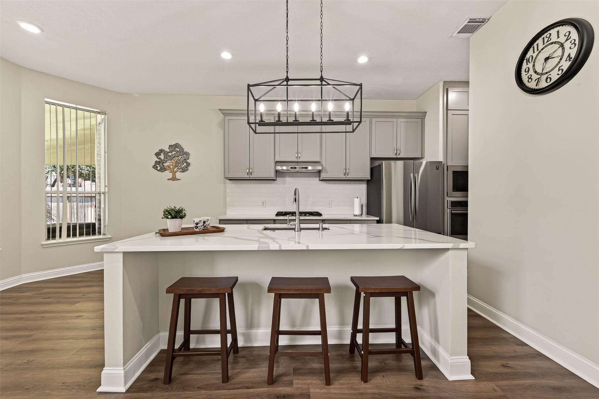 2002 Thorncrest Court, Sugar Land, TX 77479 Modern kitchen with sleek gray cabinetry, a spacious quartz island, and elegant pendant lighting. Stainless steel appliances and a cozy breakfast bar with seating enhance the space.