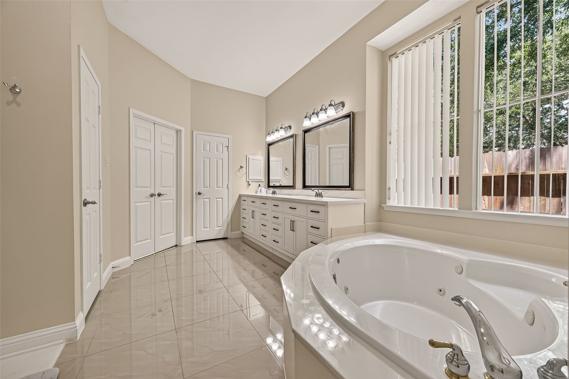 2002 Thorncrest Court, Sugar Land, TX 77479 Master bathroom featuring a luxurious soaking tub, dual vanities with elegant mirrors, and large windows for natural light.