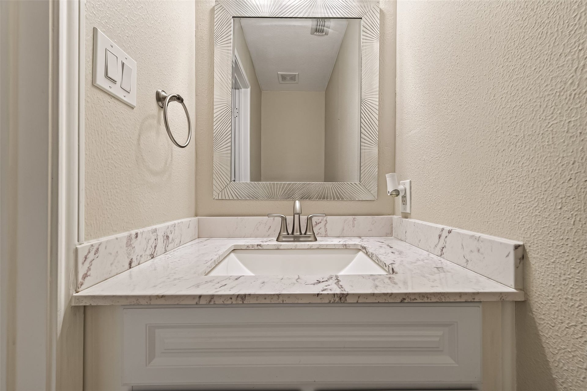 2002 Thorncrest Court, Sugar Land, TX 77479 Elegantly designed powder room vanity features a sleek marble countertop, modern fixtures, and a stylish framed mirror, creating a sophisticated and functional space.