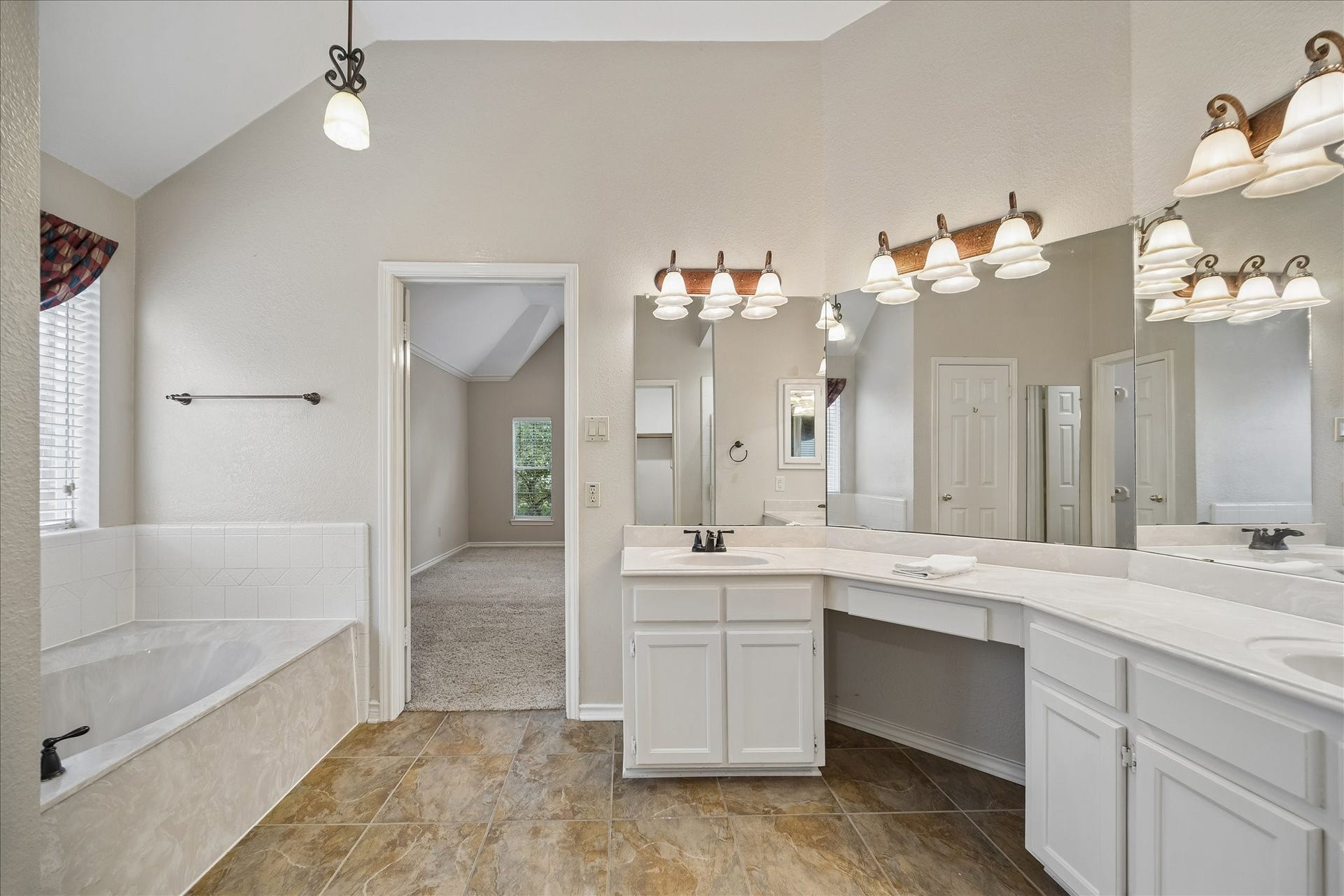 16715 Colony Terrace Drive, Sugar Land, TX 77479 This view of the primary bathroom shows you the jetted tub on the left, doorway to the bedroom and the vanity area. Behind are 2 walk-in closets.