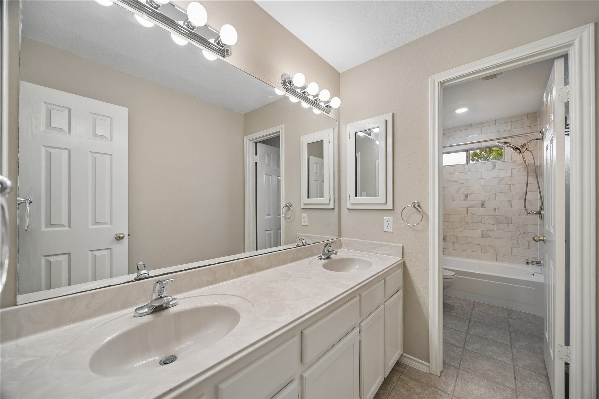 16715 Colony Terrace Drive, Sugar Land, TX 77479 This is the secondary bathroom upstairs. Dual sinks, lots of cabinets, including on through the door and on the left. Beautiful tile tub with shower and small window above.