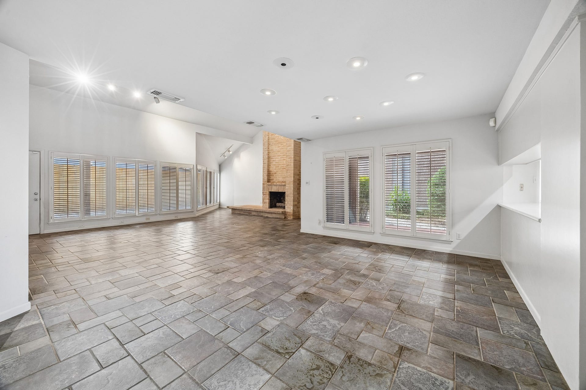 10327 Olympia Drive, Houston, TX 77042 Large open floor plan with dining area open to kitchen and family room across the back of the home. The home features floor to ceiling windows and natural tile flooring.