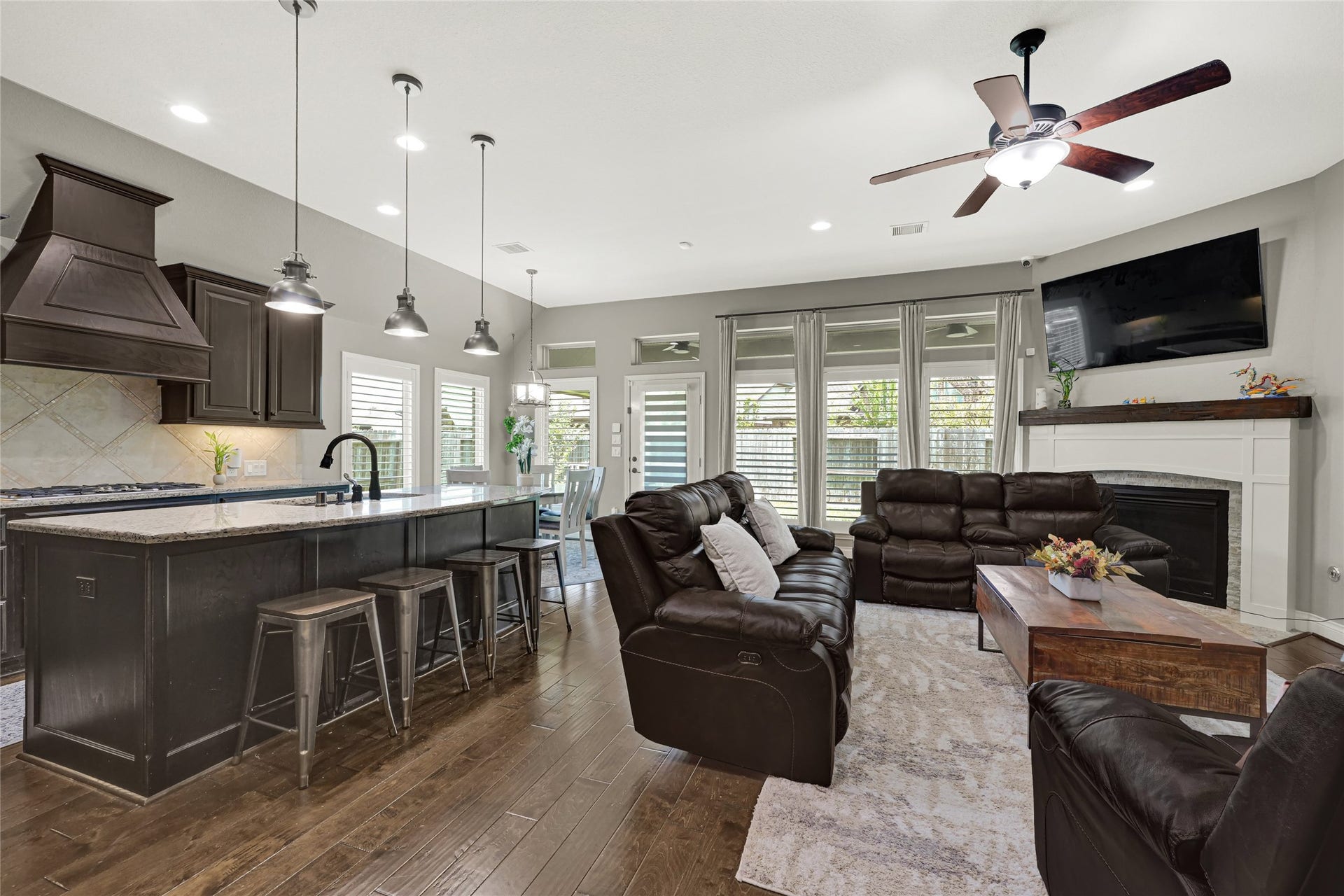Bright and inviting, this elegant kitchen seamlessly opens to the family area, featuring a large island, stainless steel appliances, and a gas stove, all bathed in abundant natural sunlight.