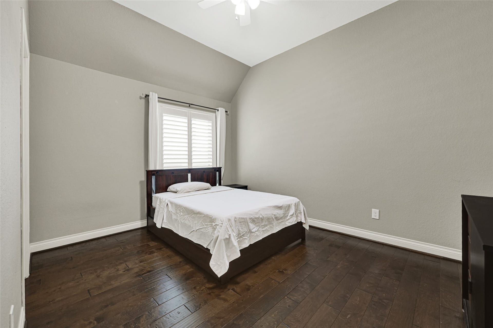 Bedroom 2 offers the luxury of a private full bath, rich wood flooring, and elegant plantation shutter windows.