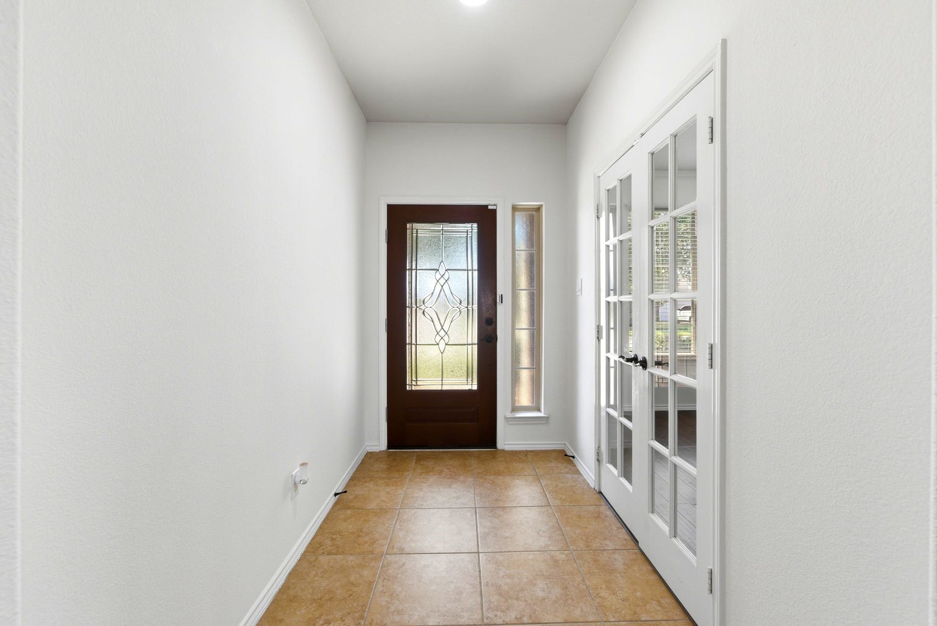 25322 Alverstone Drive, Katy, TX 77494 Inviting entryway featuring a stylish wooden door with decorative glass, complemented by elegant French doors and warm tile flooring.