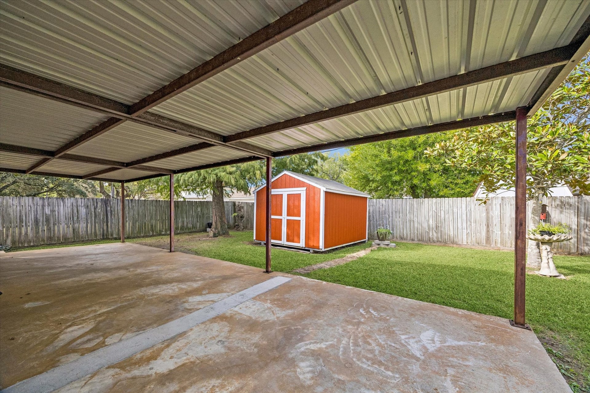 Spacious covered patio overlooking a well-maintained backyard with a  storage shed, perfect for outdoor activities and storage.