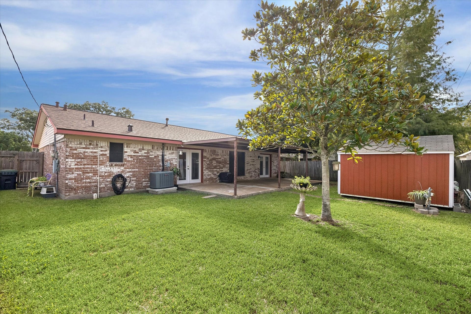 Charming backyard with a covered patio, lush lawn, and a spacious storage shed, perfect for outdoor gatherings and storage needs.