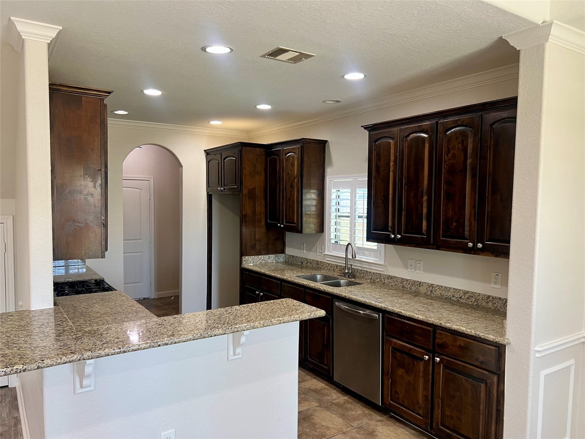 Kitchen boasts gas cooktop, SS appliances, granite countertops, double sinks, window with plantation shutters.
