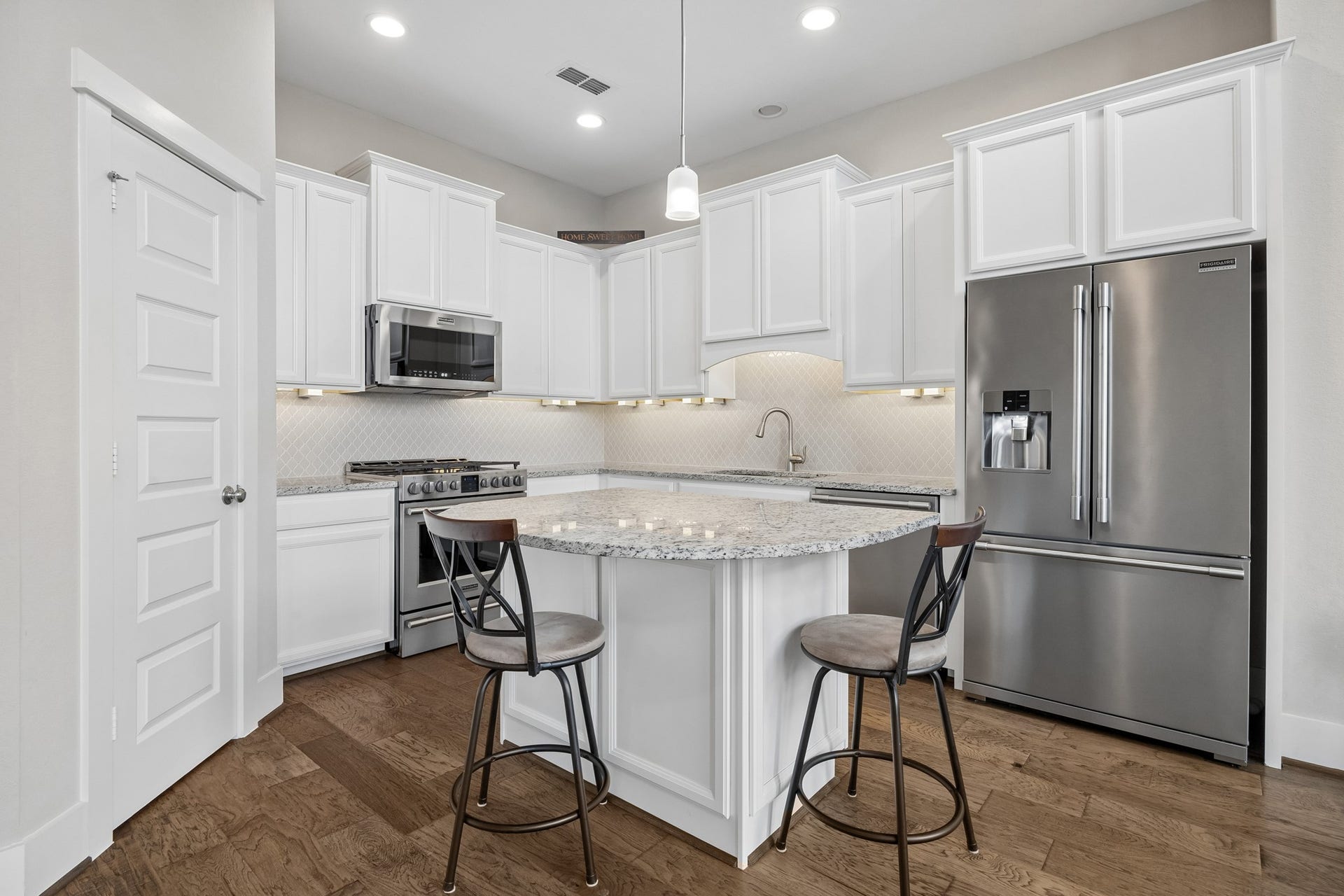 The beautiful kitchen features granite countertops, stainless steel appliances, engineered wood flooring, and a spacious walk-in pantry.