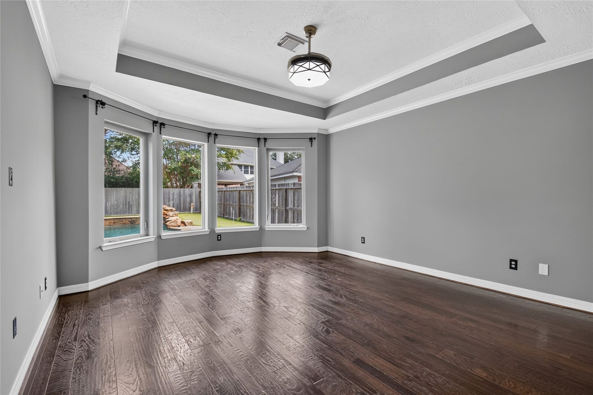11810 Rue Beaujon Court, Tomball, TX 77377 Spacious first-floor primary bedroom with REAL WOOD FLOORS, tray ceiling and a wall of windows overlooking the backyard.