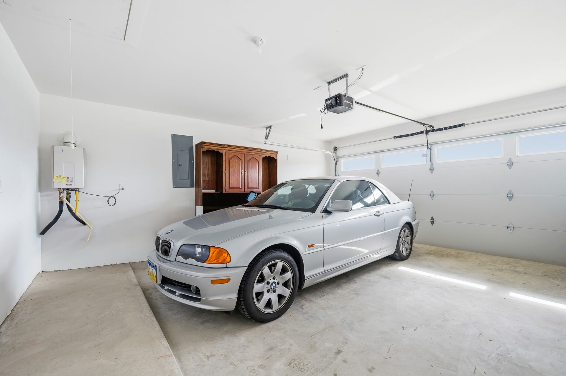 7002 Fleetwood Crescent Way, Richmond, TX 77407 This spacious garage features a clean, bright interior with a water heater and storage cabinet. It includes a large automatic door, accommodating two vehicles comfortably.