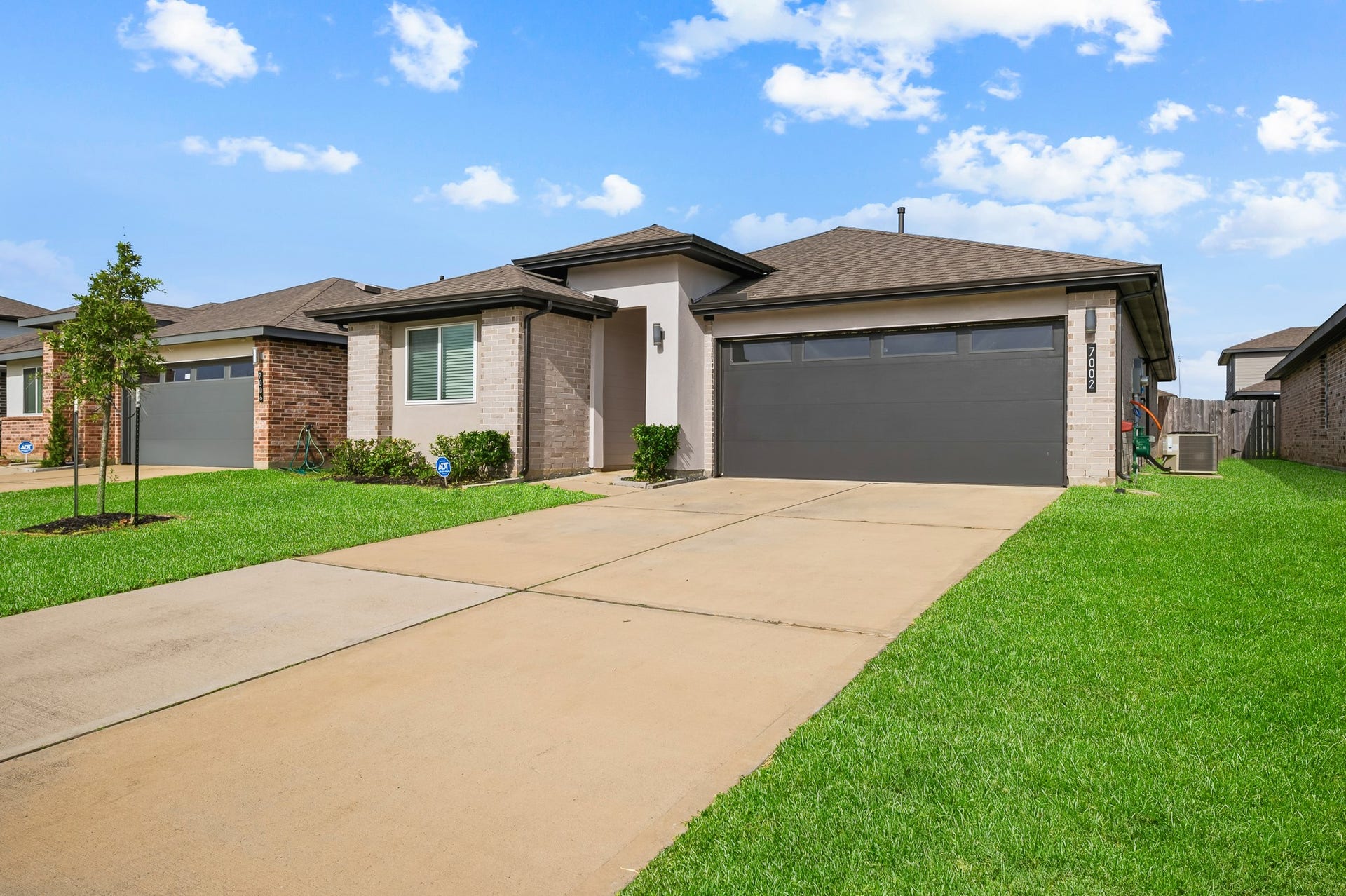 7002 Fleetwood Crescent Way, Richmond, TX 77407 Modern single-story home with a clean facade, featuring a two-car garage, well-maintained front yard, and a tidy driveway.