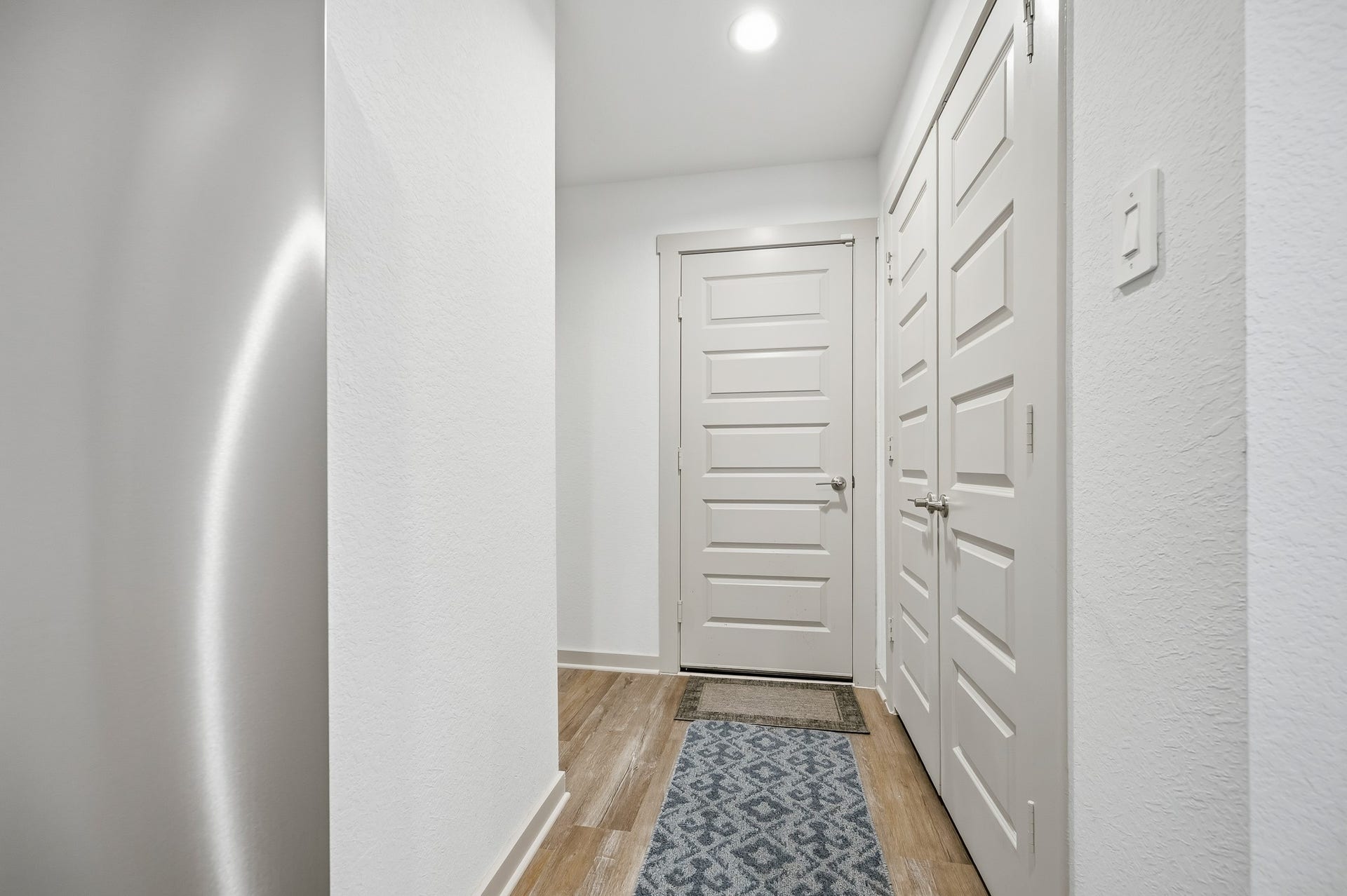7002 Fleetwood Crescent Way, Richmond, TX 77407 This photo showcases a modern hallway with light-colored walls and doors, wood flooring, and a patterned runner rug, creating a bright and welcoming entryway.