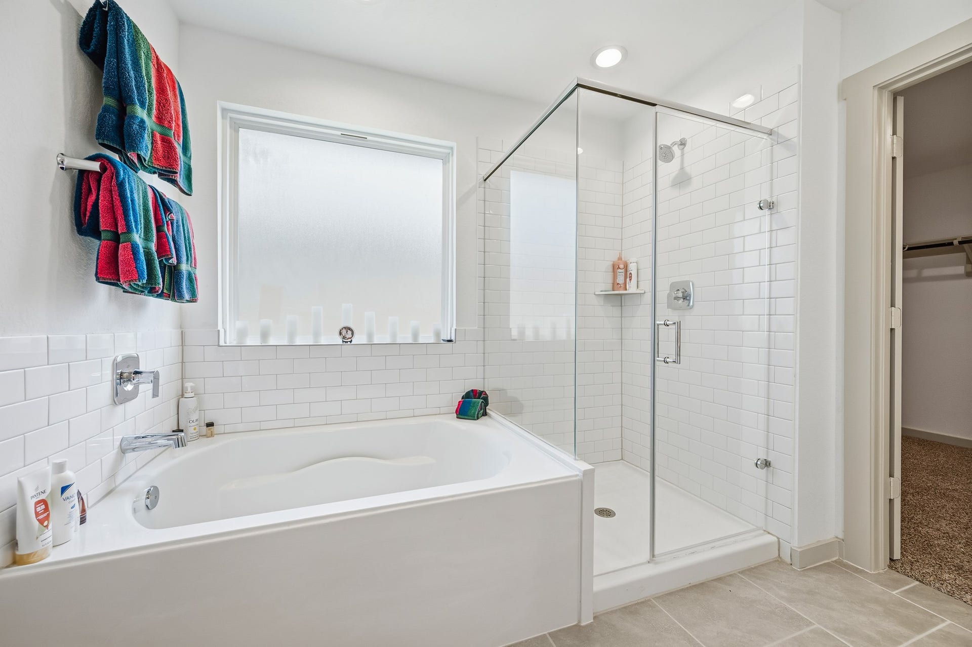 7002 Fleetwood Crescent Way, Richmond, TX 77407 This modern bathroom features a sleek glass-enclosed shower, a spacious bathtub, and a large frosted window for natural light. The white subway tiles and neutral flooring create a clean, inviting atmosphere.