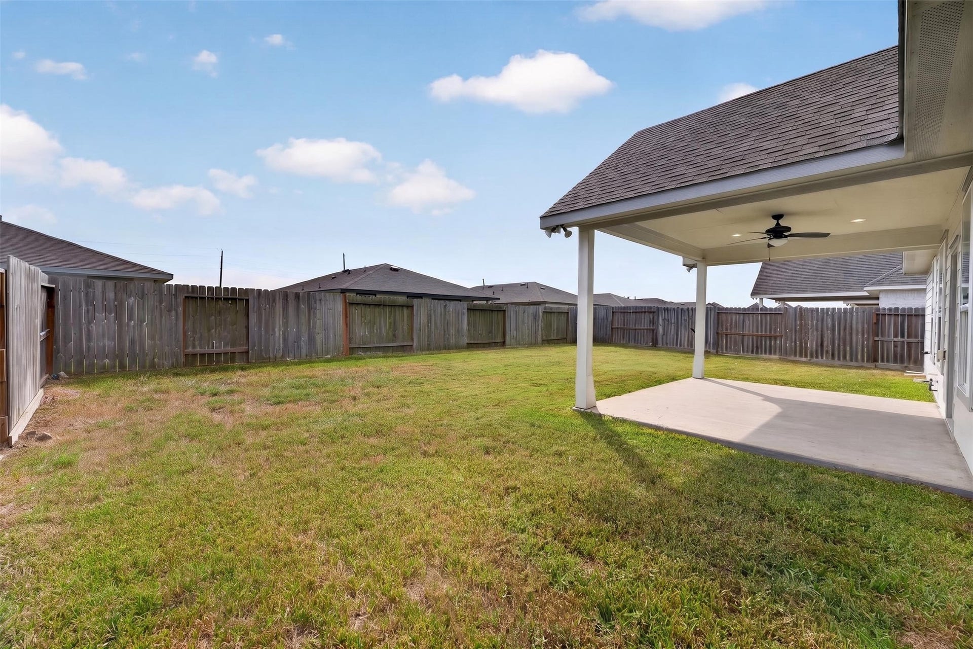 Spacious fenced backyard with a covered patio, perfect for outdoor gatherings and relaxation.