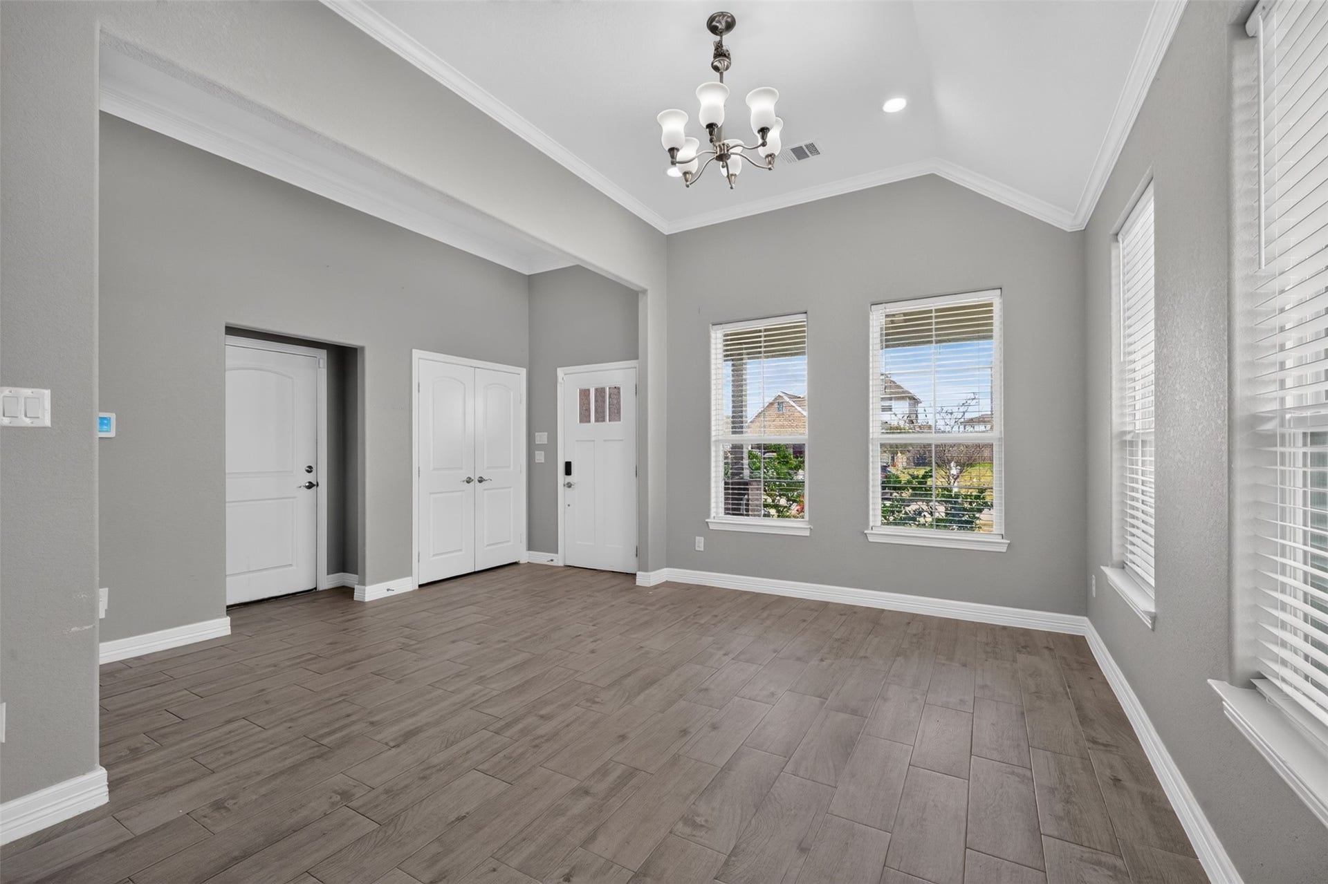 Elegant room with high ceilings, modern light fixture, and large windows offering plenty of natural light.