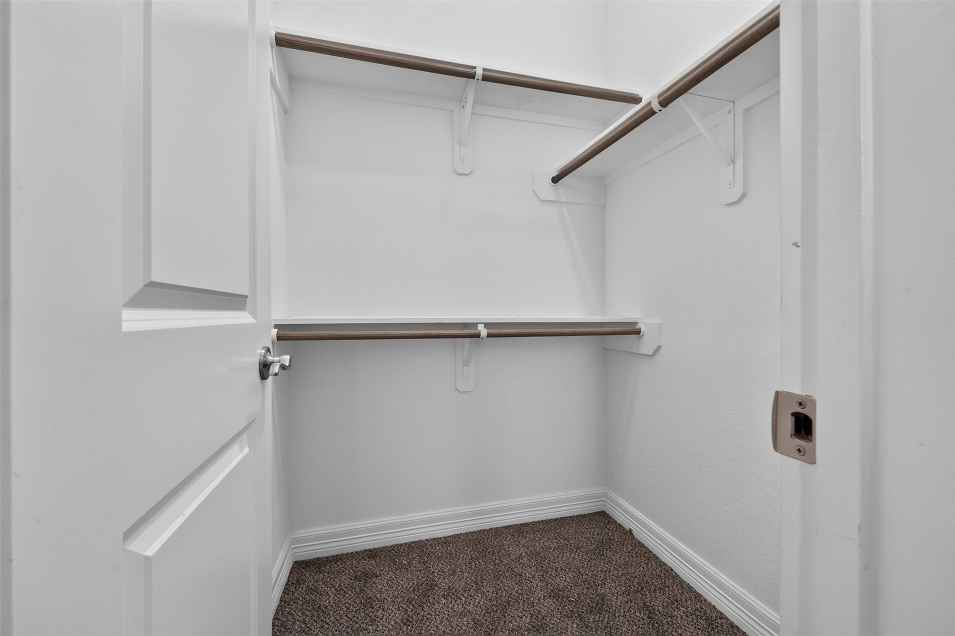 Spacious walk-in closet with dual-tier hanging rods and plush carpeting, perfect for organizing your wardrobe.