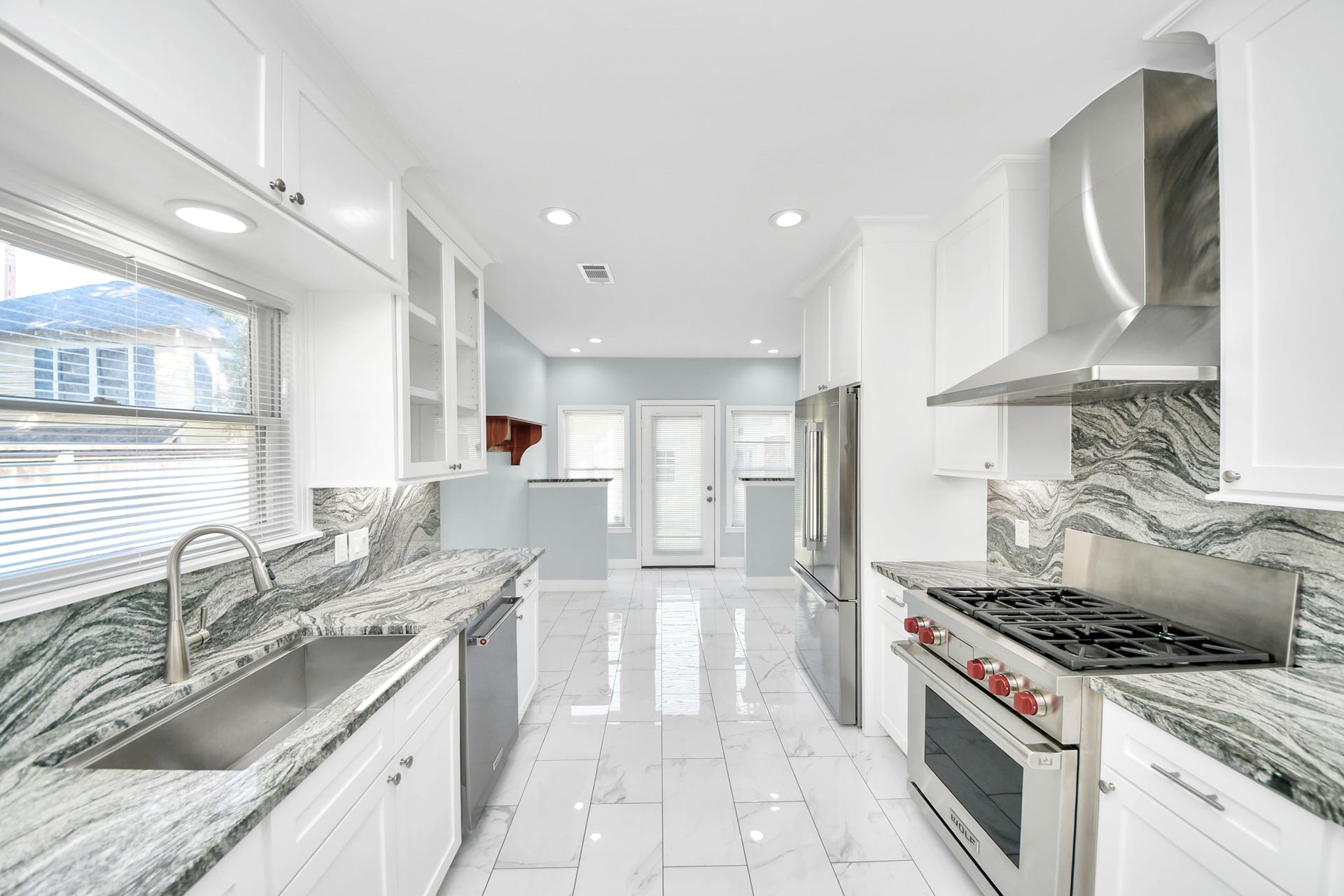 909 Fugate Street, Houston, TX 77009 Sleek, modern kitchen featuring stainless steel appliances, elegant marble countertops, and pristine white cabinetry, all illuminated by ample natural light.