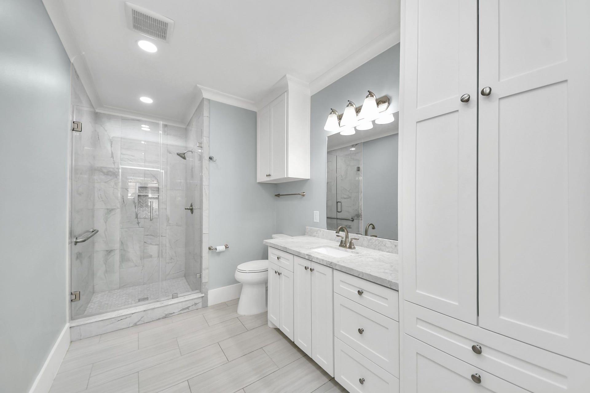 909 Fugate Street, Houston, TX 77009 Elegant and inviting, the secondary bathroom boasts a sleek tiled shower, modern fixtures, and ample storage within pristine white cabinetry, creating a serene retreat.