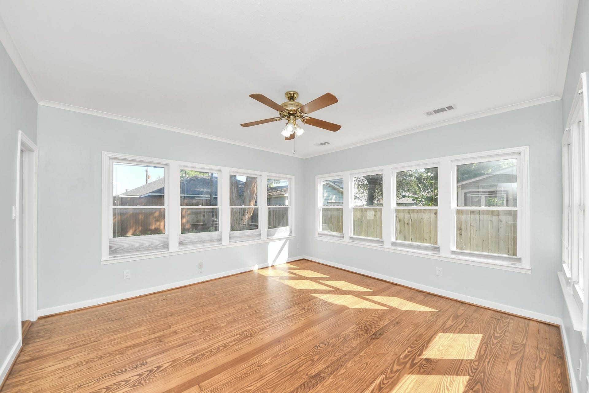 909 Fugate Street, Houston, TX 77009 Bright and relaxing primary bedroom featuring expansive windows, gleaming hardwood floors, and a ceiling fan for ultimate comfort.