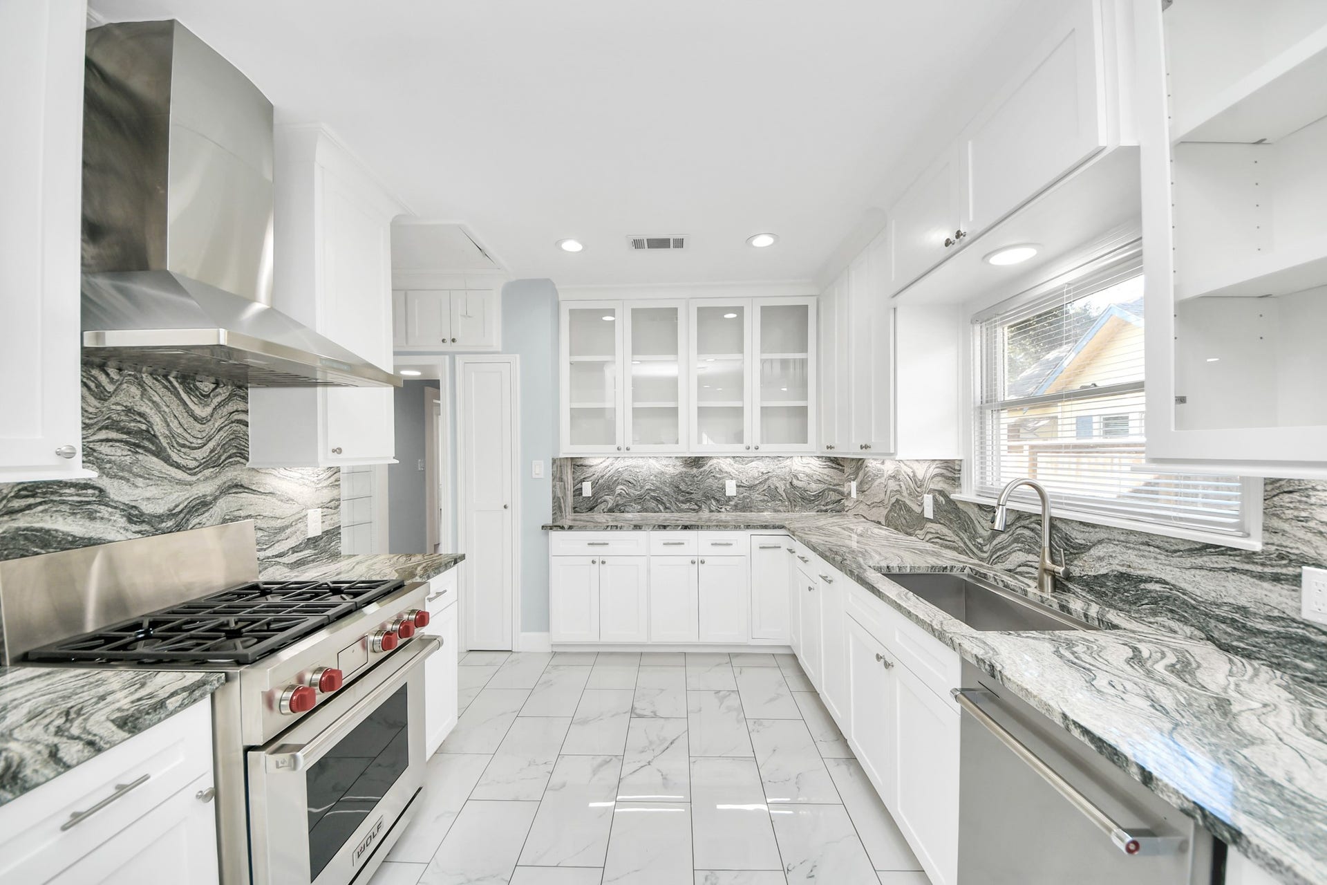 909 Fugate Street, Houston, TX 77009 Sleek kitchen featuring modern stainless steel appliances, elegant marble countertops, and ample white cabinetry, offering a bright and functional space for cooking enthusiasts.