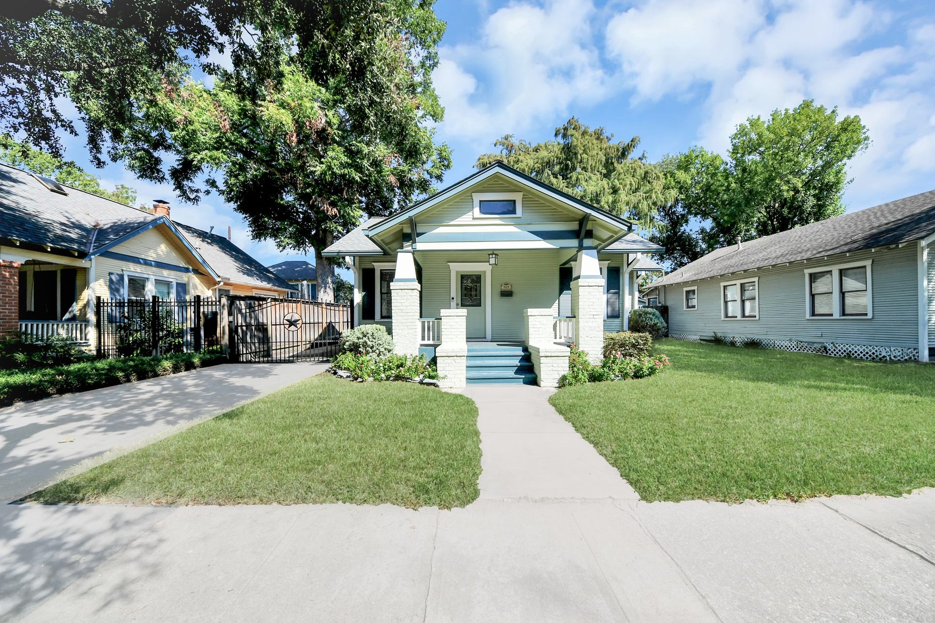 909 Fugate Street, Houston, TX 77009 Charming bungalow with a welcoming front porch, nestled between mature trees and featuring a well-maintained lawn, offering a cozy and inviting atmosphere.