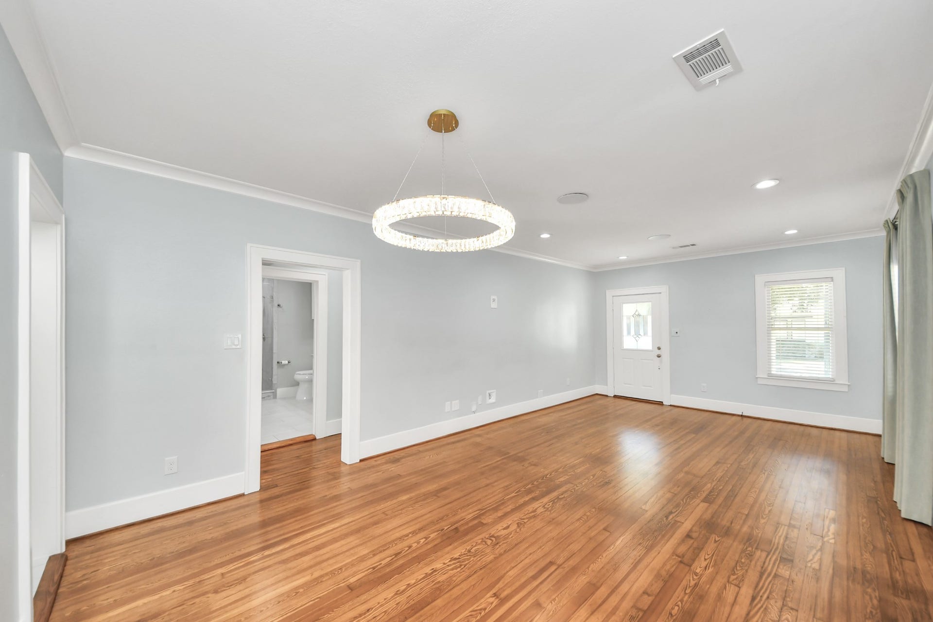 909 Fugate Street, Houston, TX 77009 Spacious living area with beautiful hardwood floors, elegant chandelier, and ample natural light from multiple windows, offering a warm and inviting ambiance.