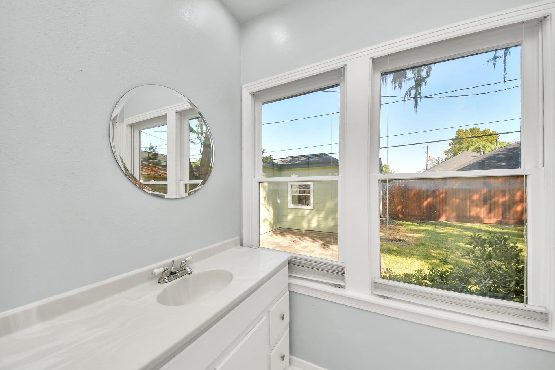 909 Fugate Street, Houston, TX 77009 Experience tranquility in the primary en suite bath with a bright, inviting atmosphere and picturesque garden views through large windows.