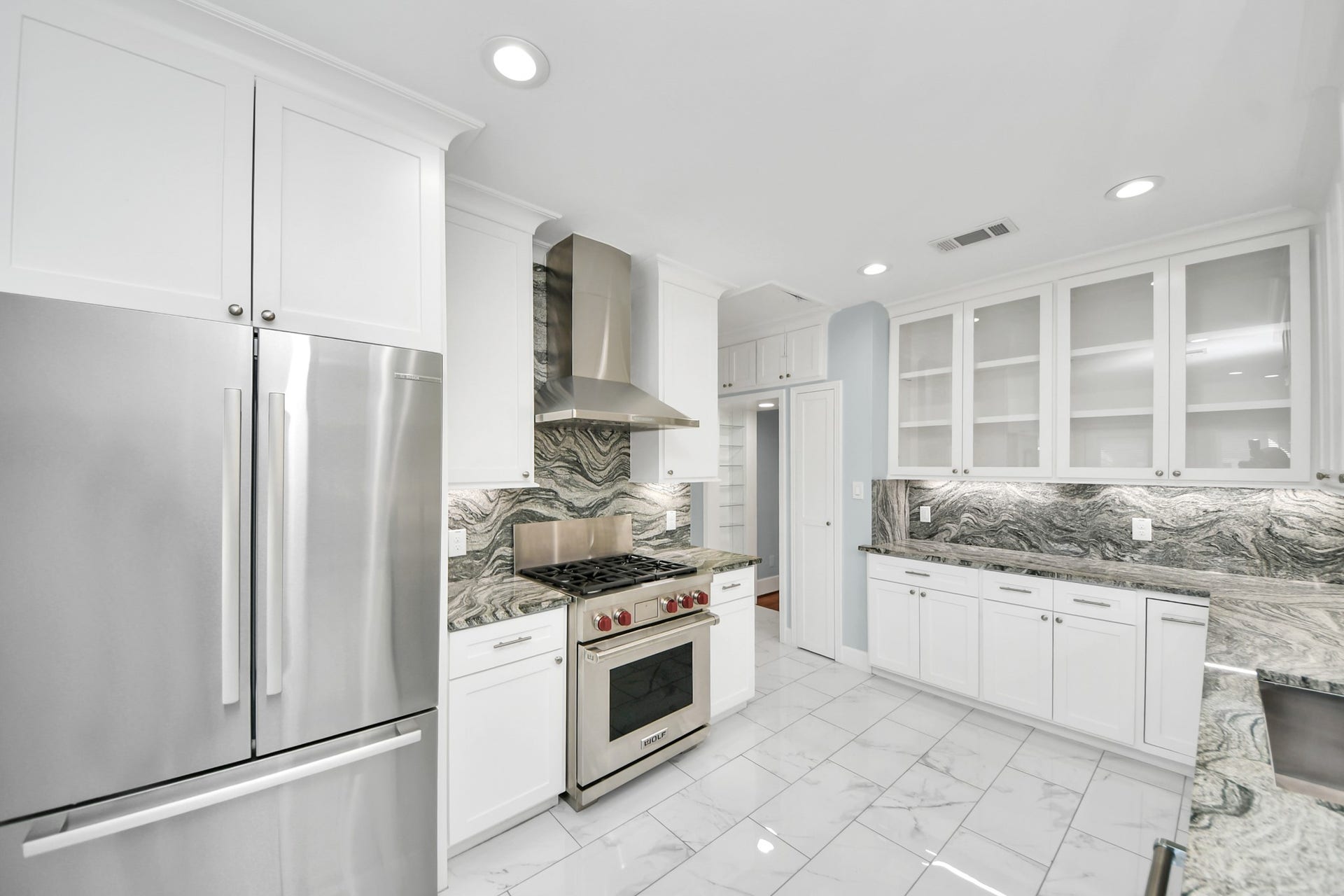 909 Fugate Street, Houston, TX 77009 Bright and modern kitchen featuring sleek stainless steel appliances, elegant white cabinetry, and striking marble countertops and backsplash.