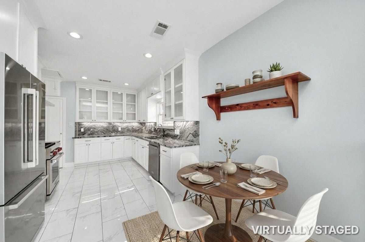909 Fugate Street, Houston, TX 77009 Modern kitchen boasts sleek stainless steel appliances, elegant marble countertops, and ample white cabinetry, complemented by a cozy dining nook with a stylish wooden table.