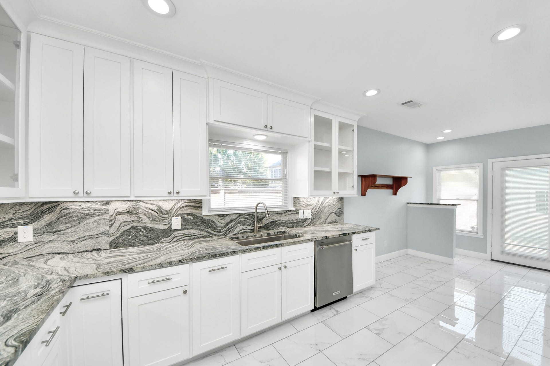 909 Fugate Street, Houston, TX 77009 Bright and modern kitchen with sleek white cabinetry, stunning marble countertops, and stainless steel appliances, offering a perfect space for culinary creativity.