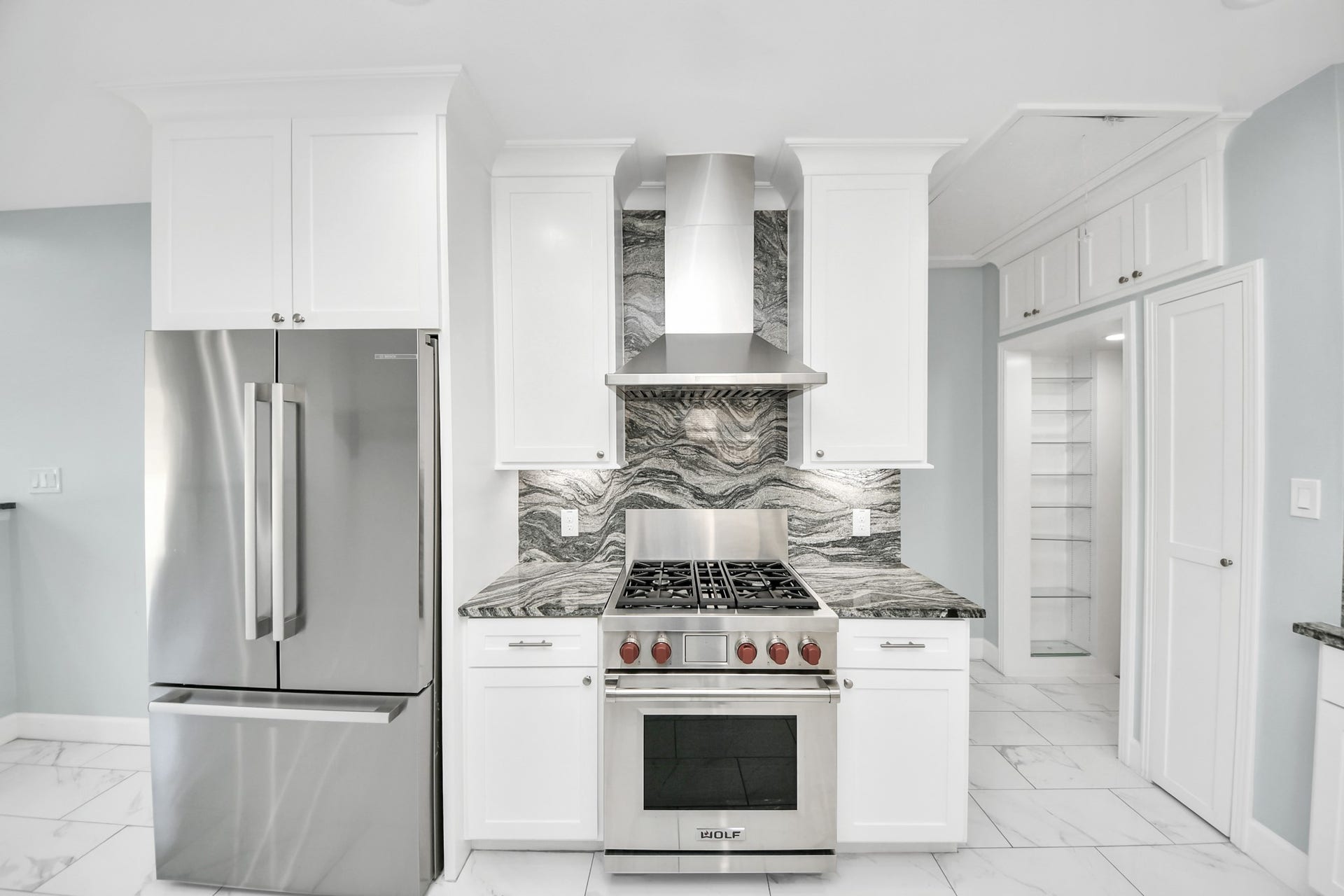 909 Fugate Street, Houston, TX 77009 Modern kitchen featuring sleek stainless steel appliances, elegant marble countertops, and ample white cabinetry for a sophisticated look.