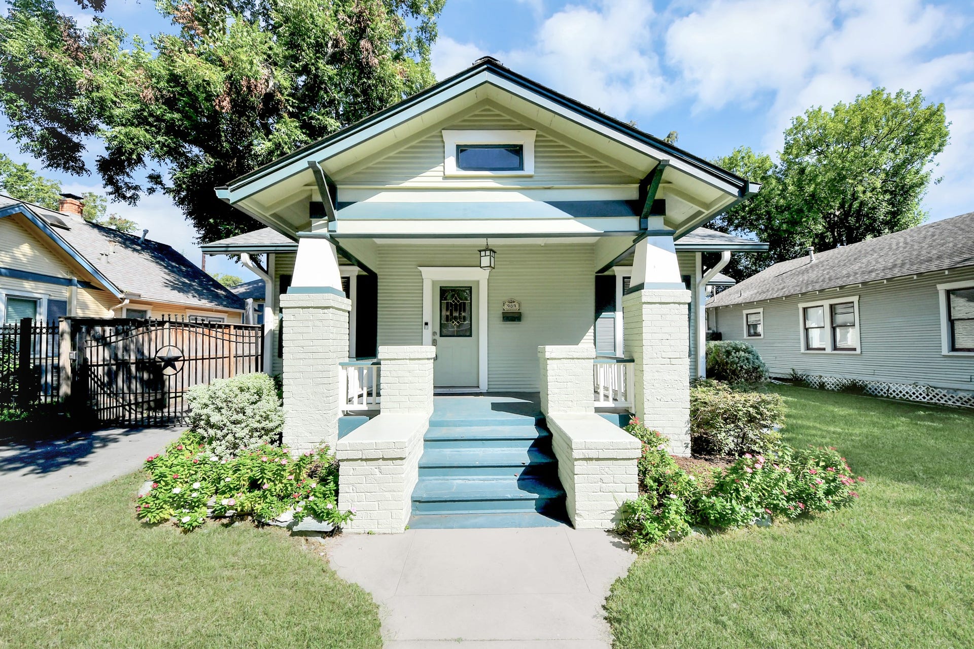 909 Fugate Street, Houston, TX 77009 Charming bungalow with inviting front porch, nestled in a lush garden setting, perfect for enjoying peaceful neighborhood views.