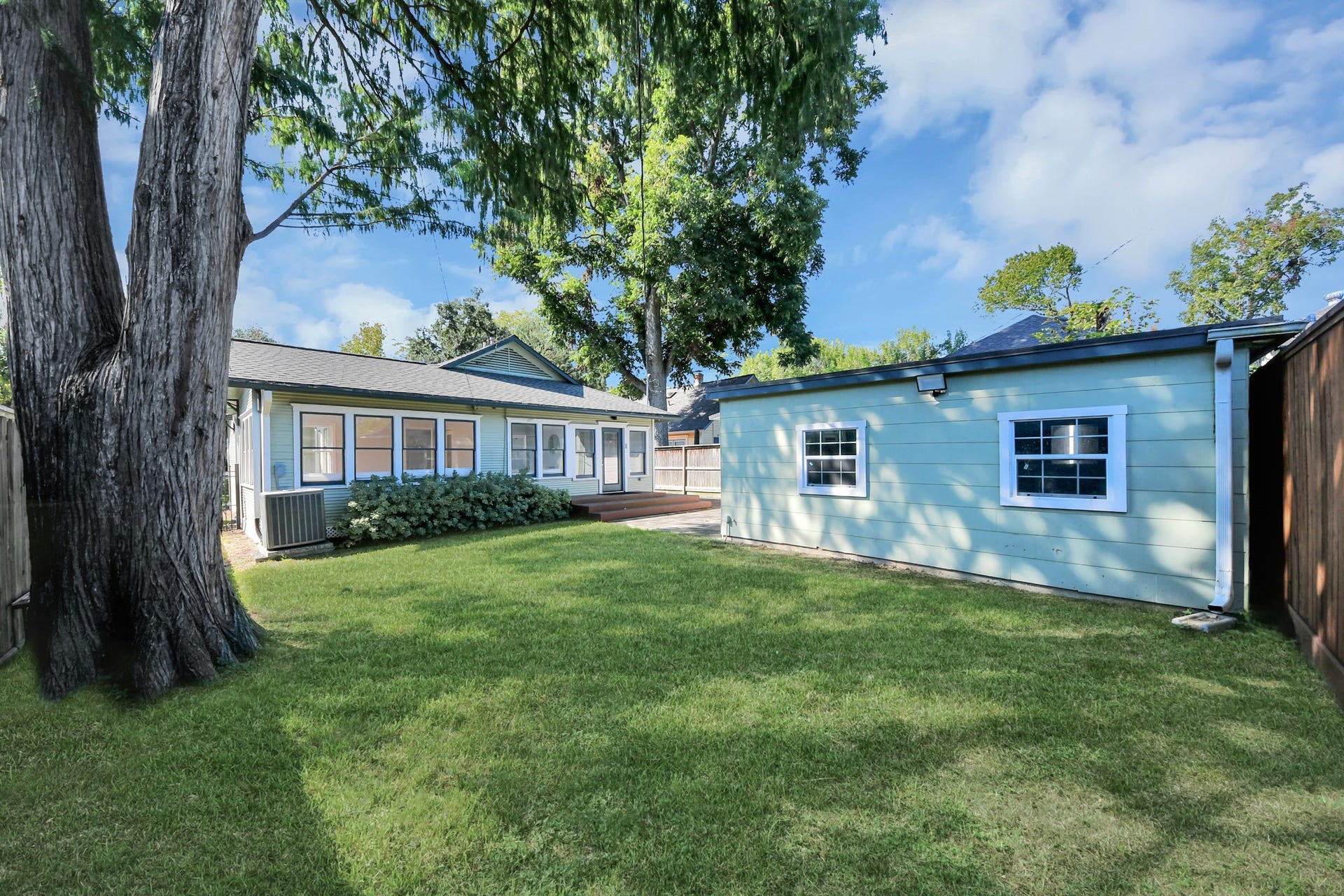 909 Fugate Street, Houston, TX 77009 Charming backyard with lush green lawn and mature trees, offering ample space for outdoor activities and relaxation.