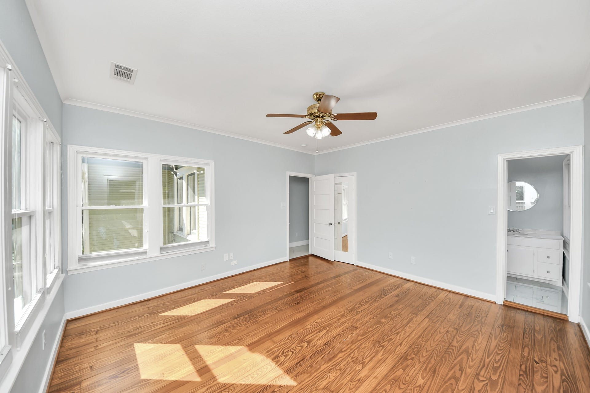 909 Fugate Street, Houston, TX 77009 Spacious and bright, the primary bedroom features gleaming hardwood floors, abundant natural light from large windows, and a ceiling fan, creating a serene retreat.