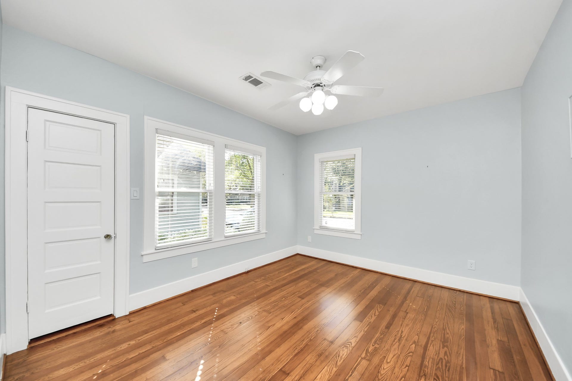 909 Fugate Street, Houston, TX 77009 Experience the charm of Bedroom 3, featuring gleaming hardwood floors, abundant natural light from large windows, and a soothing light blue palette that creates a serene retreat.
