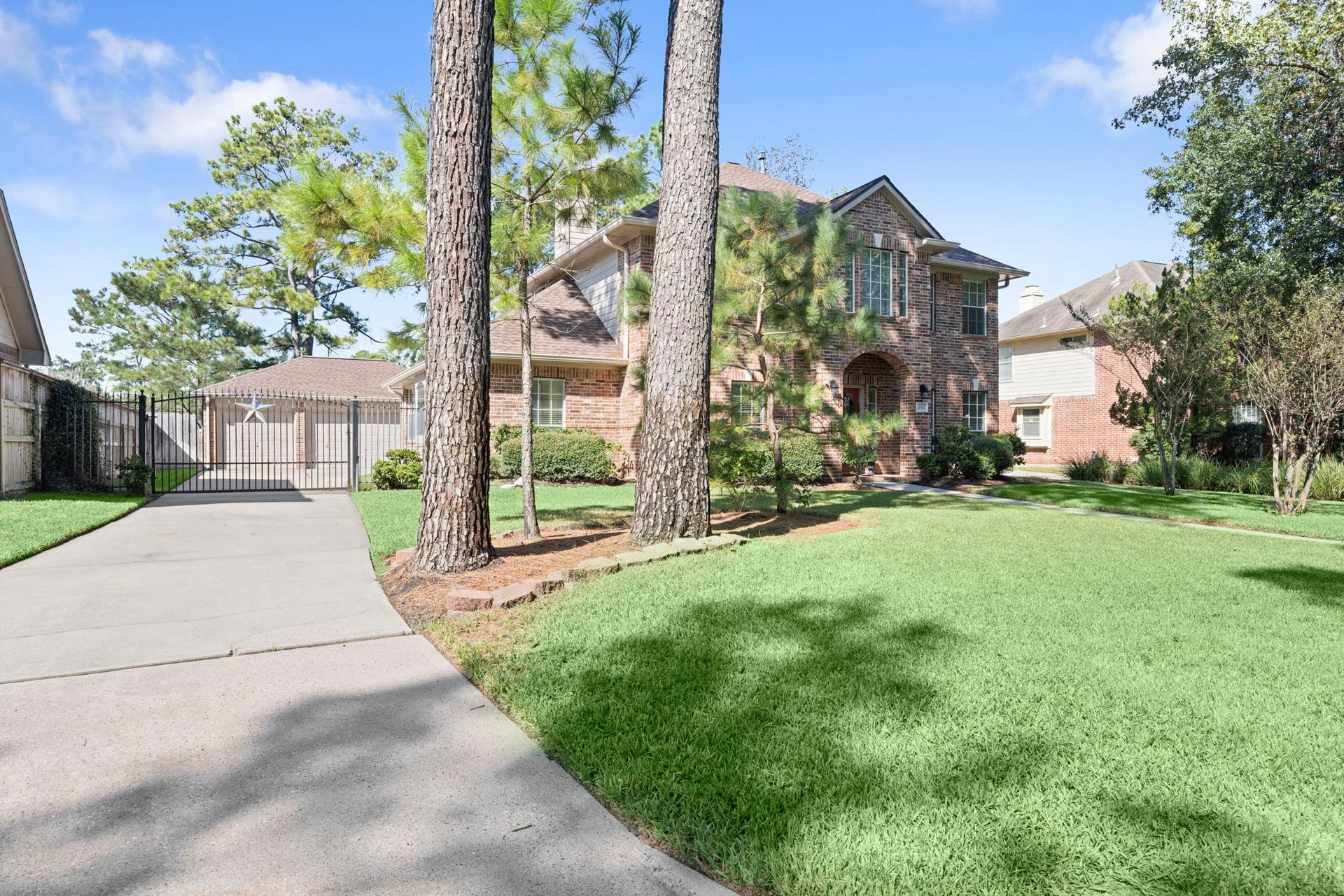 24815 Giltspur Way, Spring, TX 77389 CURB APPEAL THAT MAKES A STATEMENT! Majestic mature pines frame the expansive front lawn, while an extra-long driveway with decorative wrought-iron gate leads to the detached 3-car garage. A covered walkway connects the garage to the home, adding everyday convenience to this beautifully established setting!