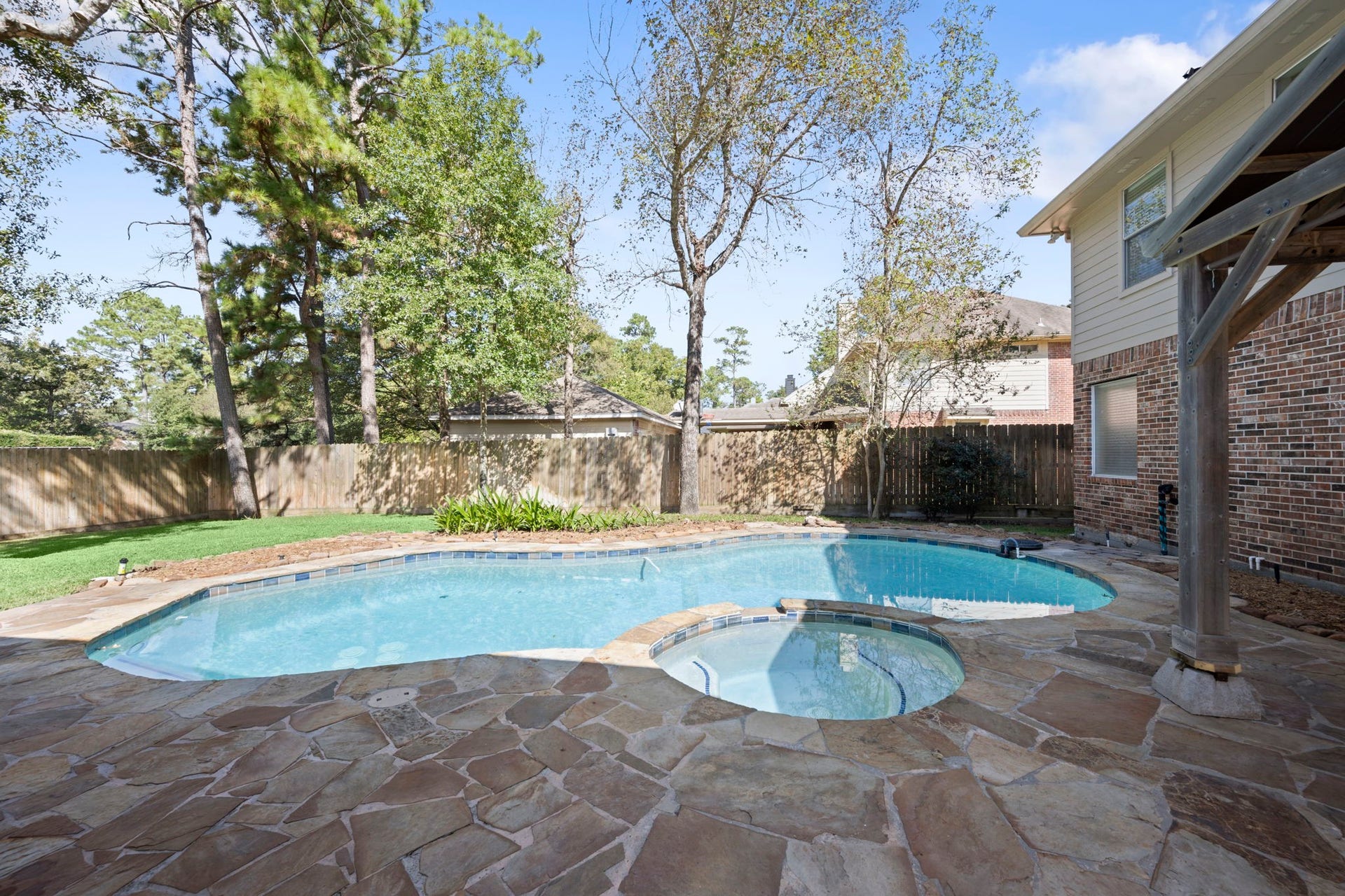 24815 Giltspur Way, Spring, TX 77389 JUST IMAGINE THE MEMORIES YOU'LL MAKE! Sunny afternoons in the sparkling freeform pool, relaxing in the adjoining spa, and unforgettable gatherings with family and friends! Beautiful flagstone decking, mature shade trees, lush landscaping, and a wood privacy fence with a reinforced 24-inch base add to this inviting backyard retreat. Why vacation when you can STAYCATION?