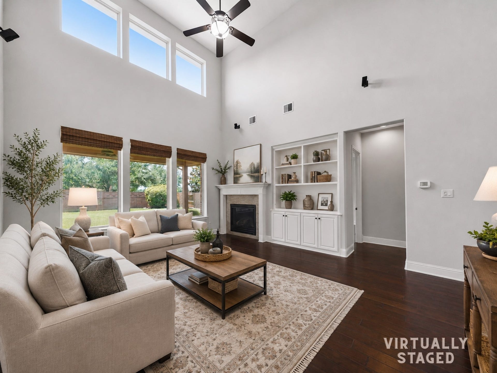 11531 Abriola Court, Richmond, TX 77406 The soaring family room has been virtually staged to showcase its incredible scale, where two-story ceilings, abundant natural light, custom built-ins, and a striking fireplace come together to create an inviting space for gathering.