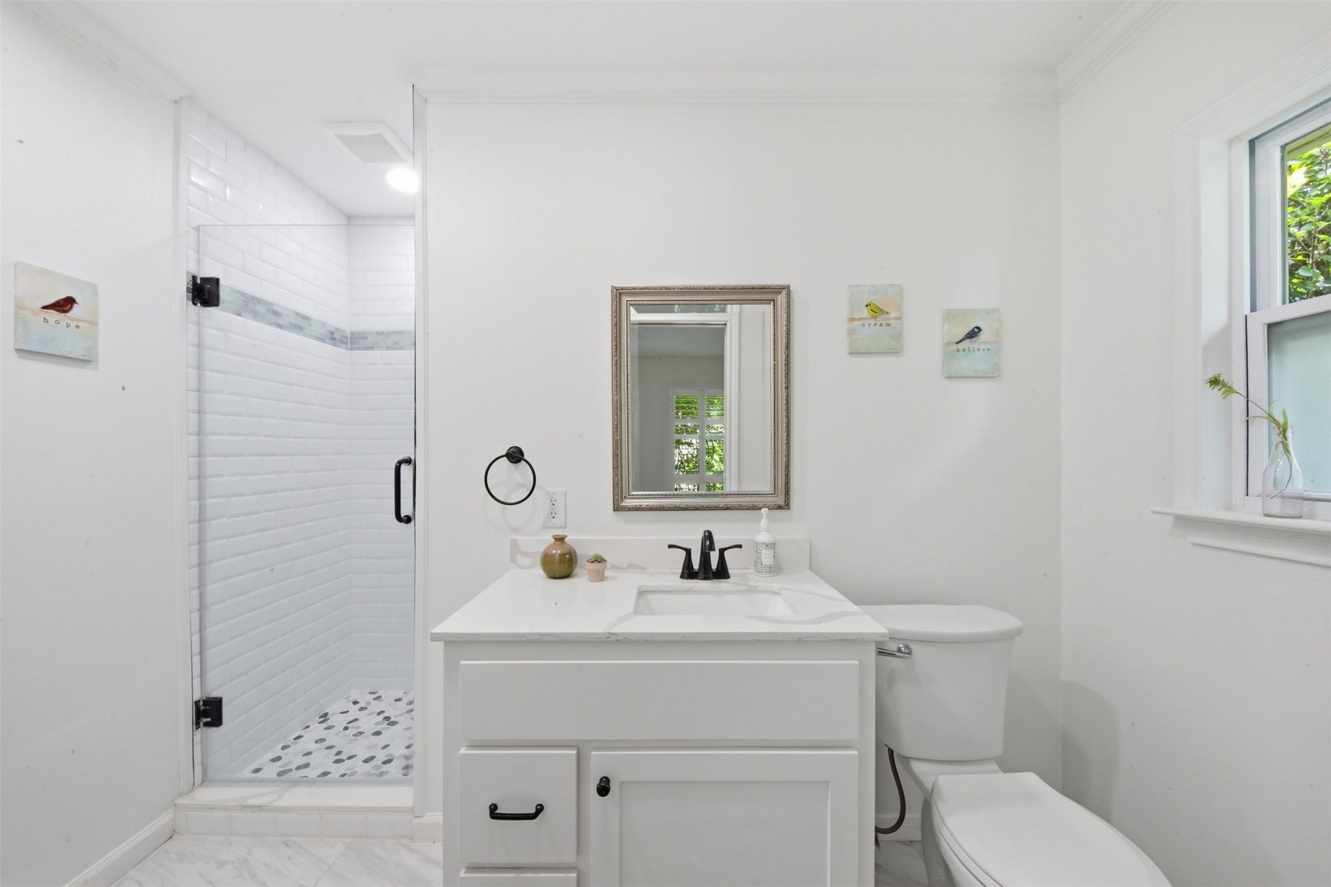 410 Kyle Street, Sugar Land, TX 77478 The renovated primary en-suite bath features a new vanity, tiled shower with tile surround, updated plumbing fixtures, new tile flooring, recessed lighting, a pocket door, and a new toilet, all part of a thoughtfully redesigned layout.