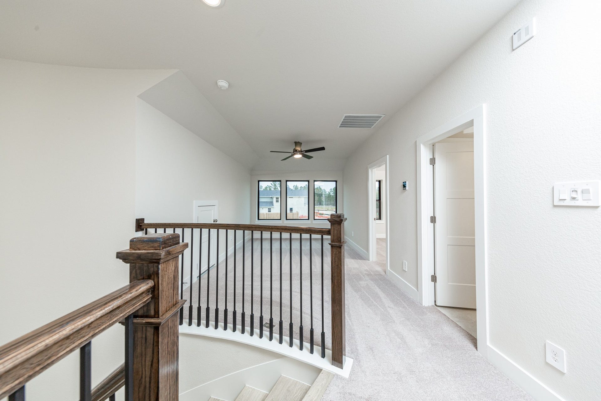 Second floor hallway showcasing the gorgeous stair railing and views of the Game Room and entrance doors to secondary bedrooom and bathroom.