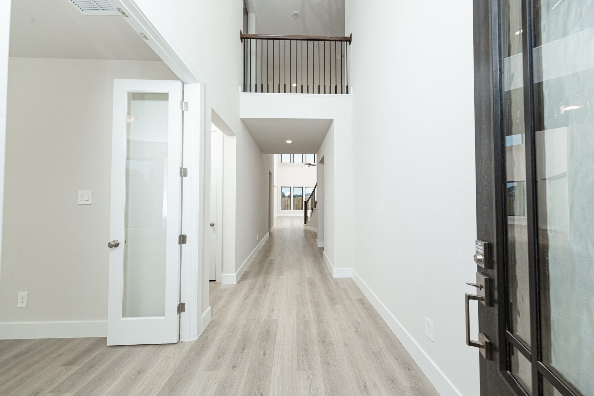 A bright and open interior entryway focuses on modern design and natural light. The space is amplified by high ceilings, recessed lighting, gorgeous laminate flooring - creating an airy and welcoming first impression.