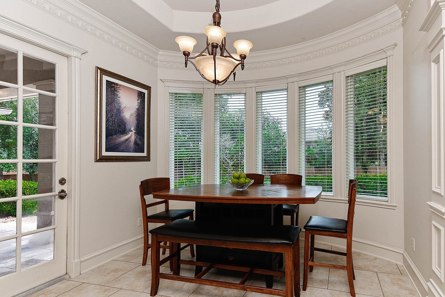 10 Snow Pond Place, The Woodlands, TX 77382 The informal dining area features distinctive architectural elements, including a recessed ceiling and a curved window bay accented by intricate molding. These expansive windows offer picturesque views of the swimming pool, while a glass door provides convenient access to the lanai.
