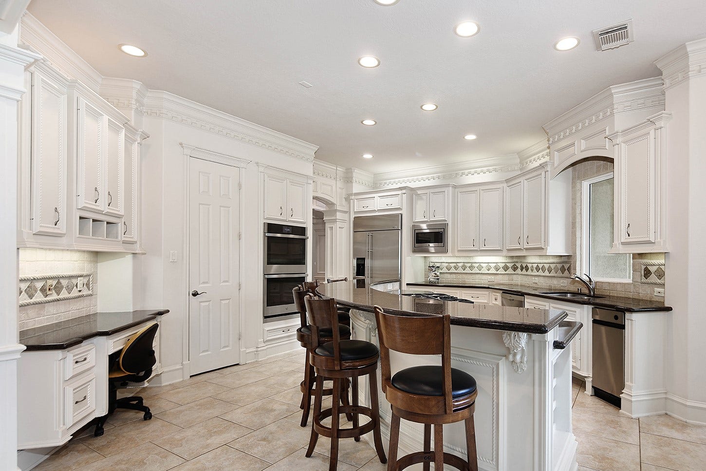 10 Snow Pond Place, The Woodlands, TX 77382 This thoughtfully designed kitchen maximizes space efficiency, featuring a center island equipped with a cooktop, integrated breakfast bar, and a dedicated chef's workstation. The space is elegantly appointed with custom cabinetry, granite countertops, and premium stainless steel appliances.